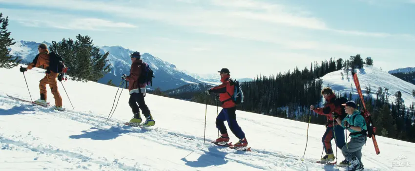 Group of people skiing uphill on a mountain slope.